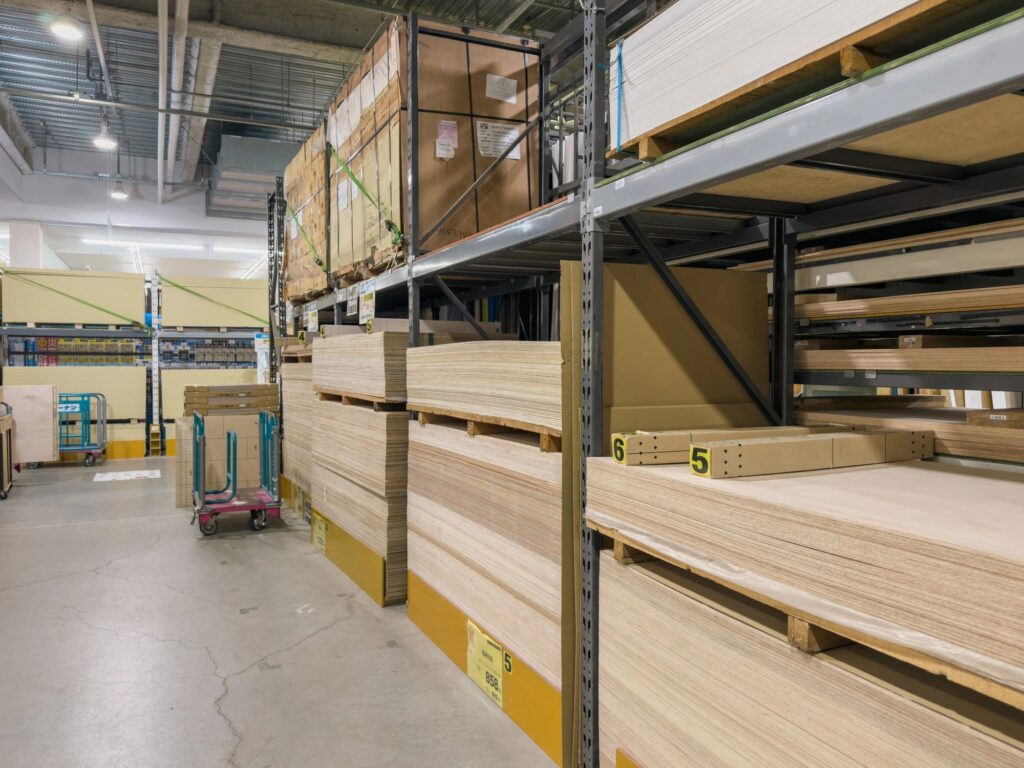 Wide aisle of a lumber store with stacked plywood panels on tall industrial shelving